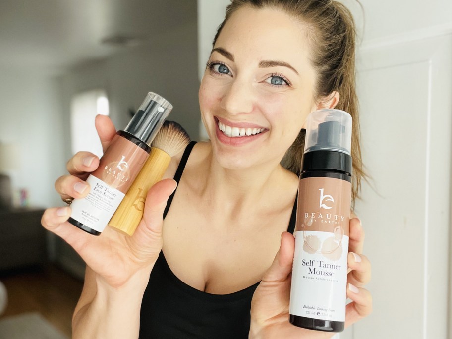 woman holding up Beauty By Earth products
