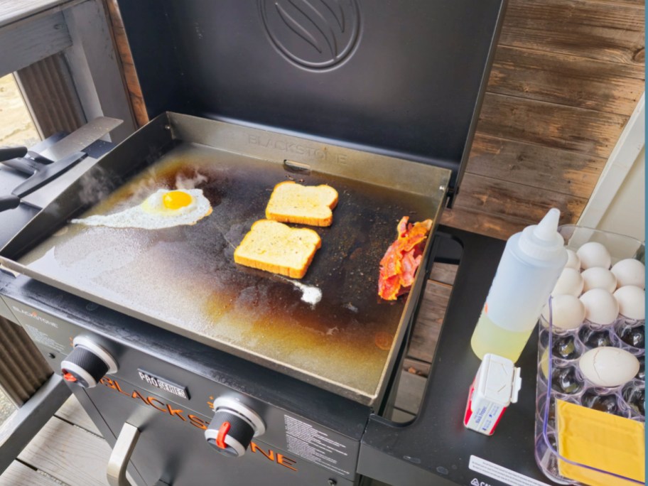 Blackstone griddle with bread eggs and bacon being cooked