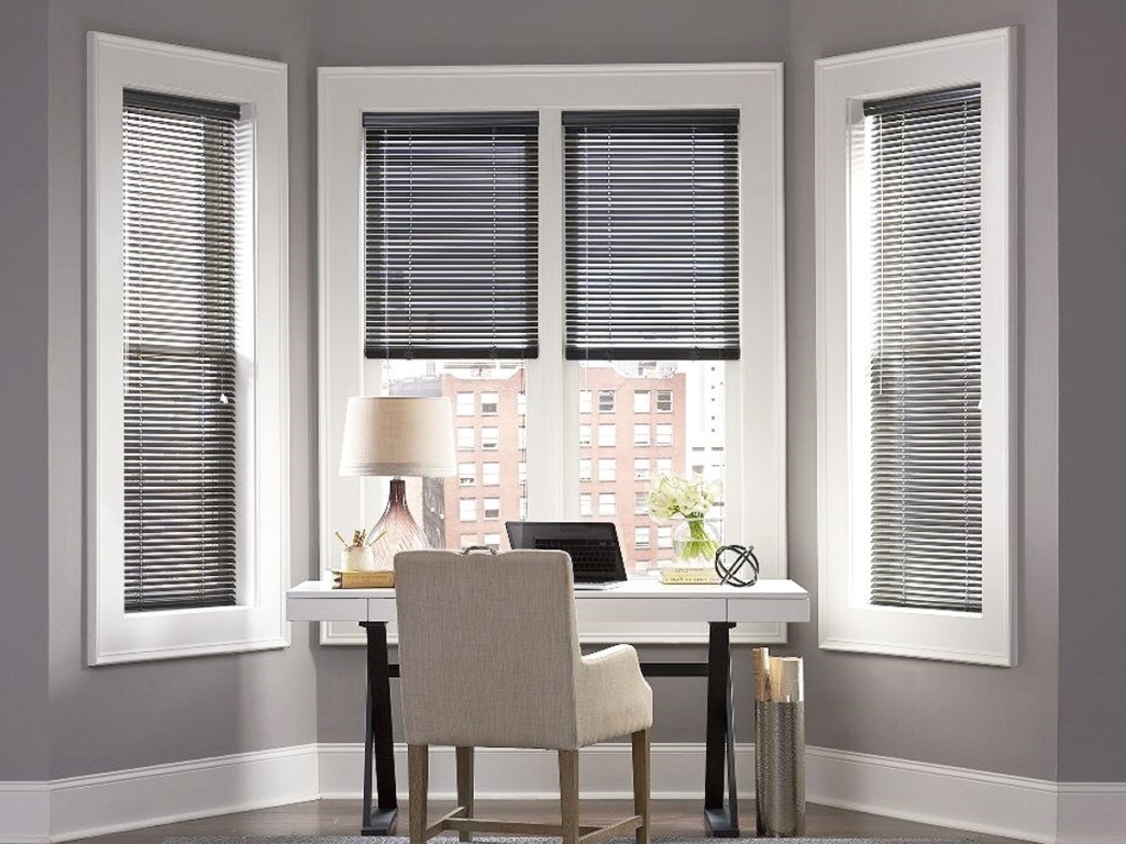 blinds in 3 windows in front of a desk