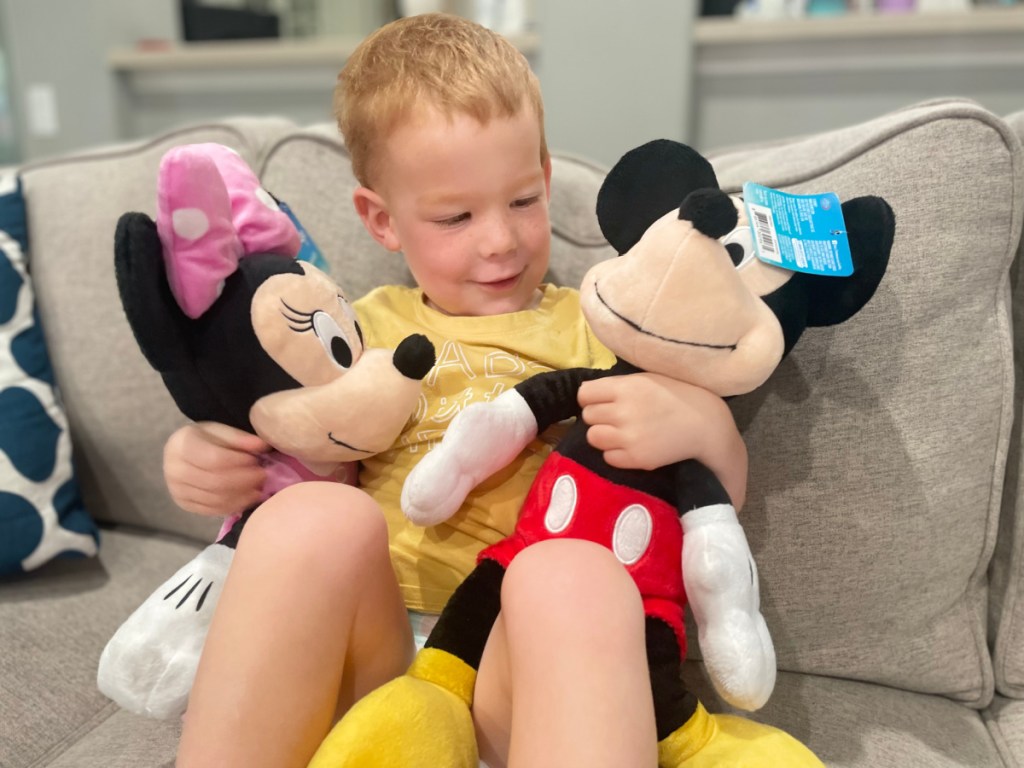 Boy holding a mickey Mouse and Minnie Mouse plush toys from Walmart