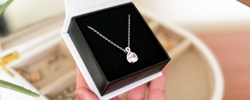 hand holding up pendant necklace in jewelry box