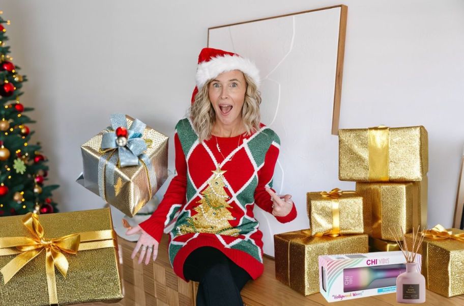 woman wearing christmas sweater and santa hat surrounded by gold presents