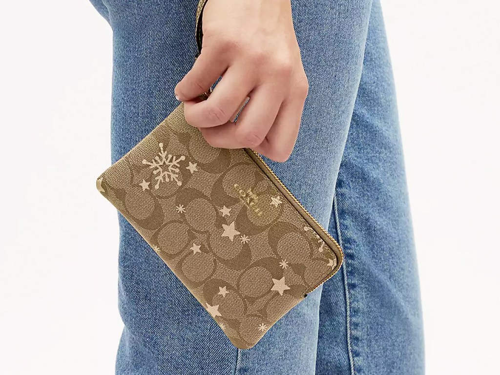 woman holding a star and snowflake print coach wristlet