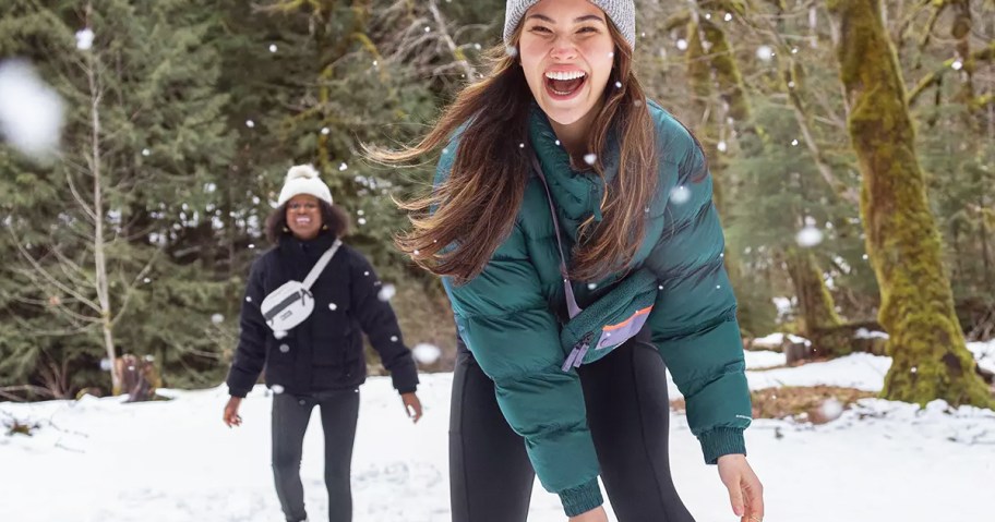 two women playing in snow wearing jackets and leggings