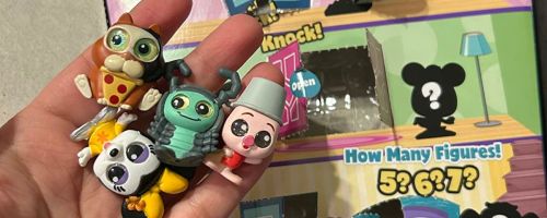 A hand holding Disney Doorables with package behind