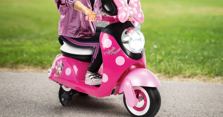 girl riding on a pink minnie mouse scooter