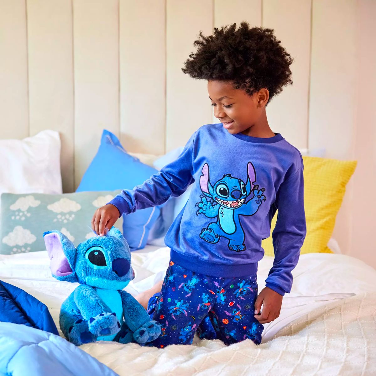 a little boy wearing Disney stitch sleepwear and playing with a disney stitch plush
