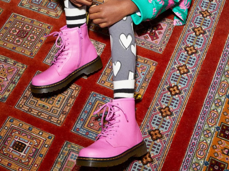 girl sitting on floor wearing bright pink combat boots