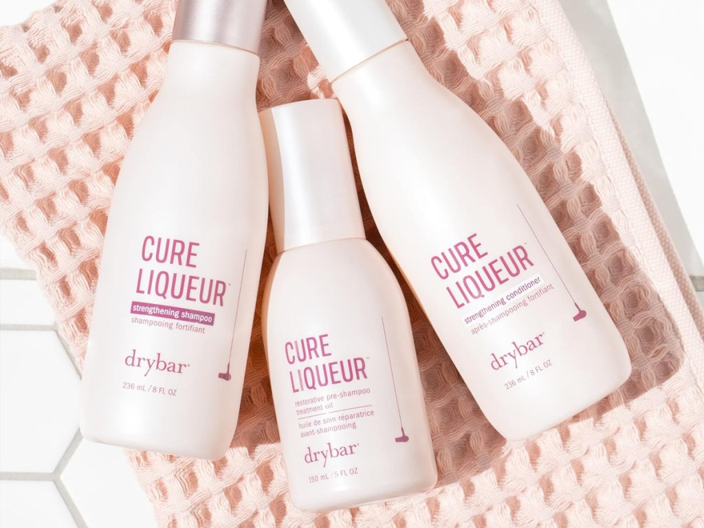 three light pink bottles of Drybar Cure Liqueur products