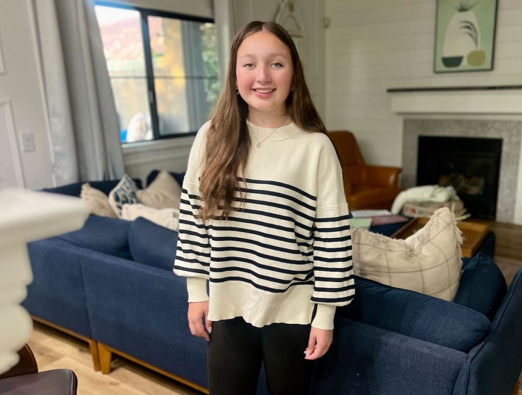 Teen girl posing in living room, wearing striped white and navy blue sweater