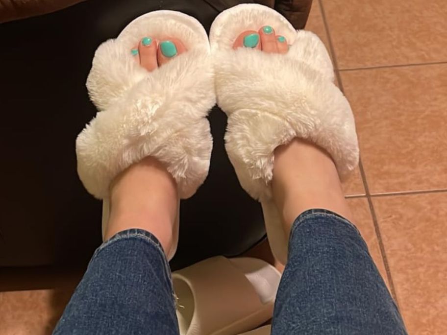 A woman wearing a pair of white fuzzy slippers