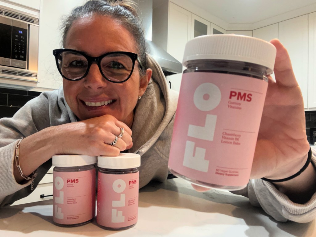 woman holding bottle of FLO PMS Gummy Vitamins 
