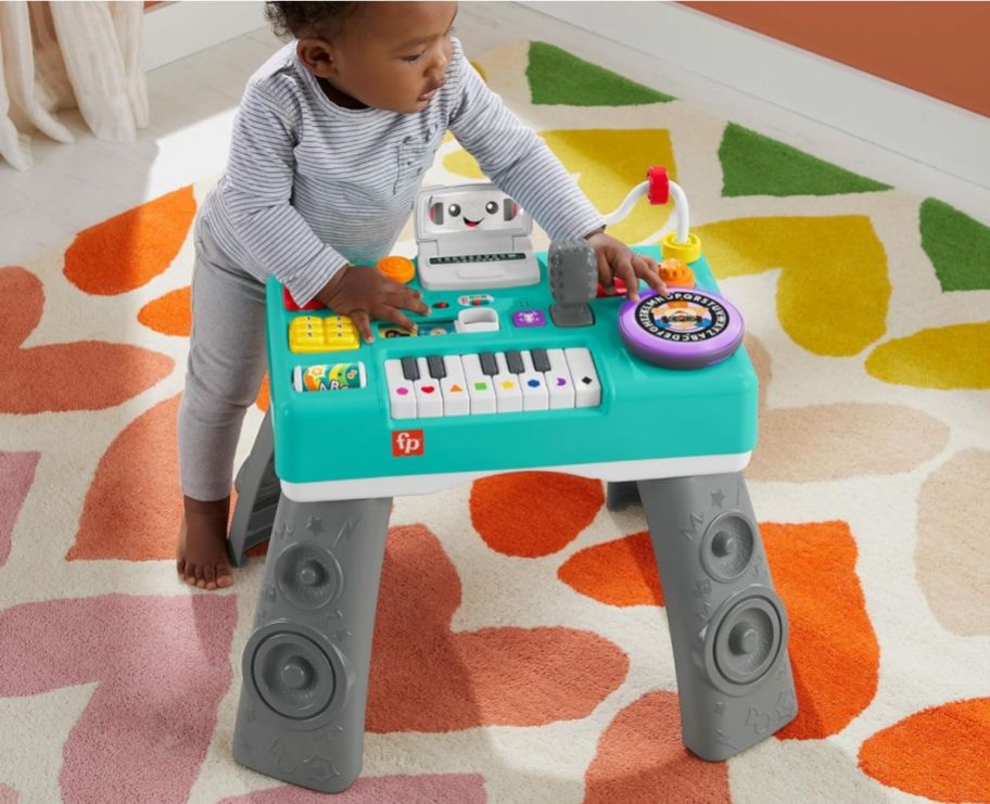 a little toddler playing with the Fisher price mix and learn dj table