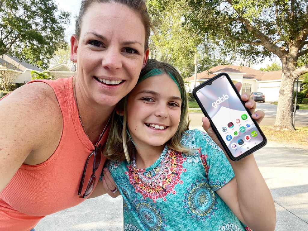 little girl holding up cell phone with Gabb on screen next to older woman