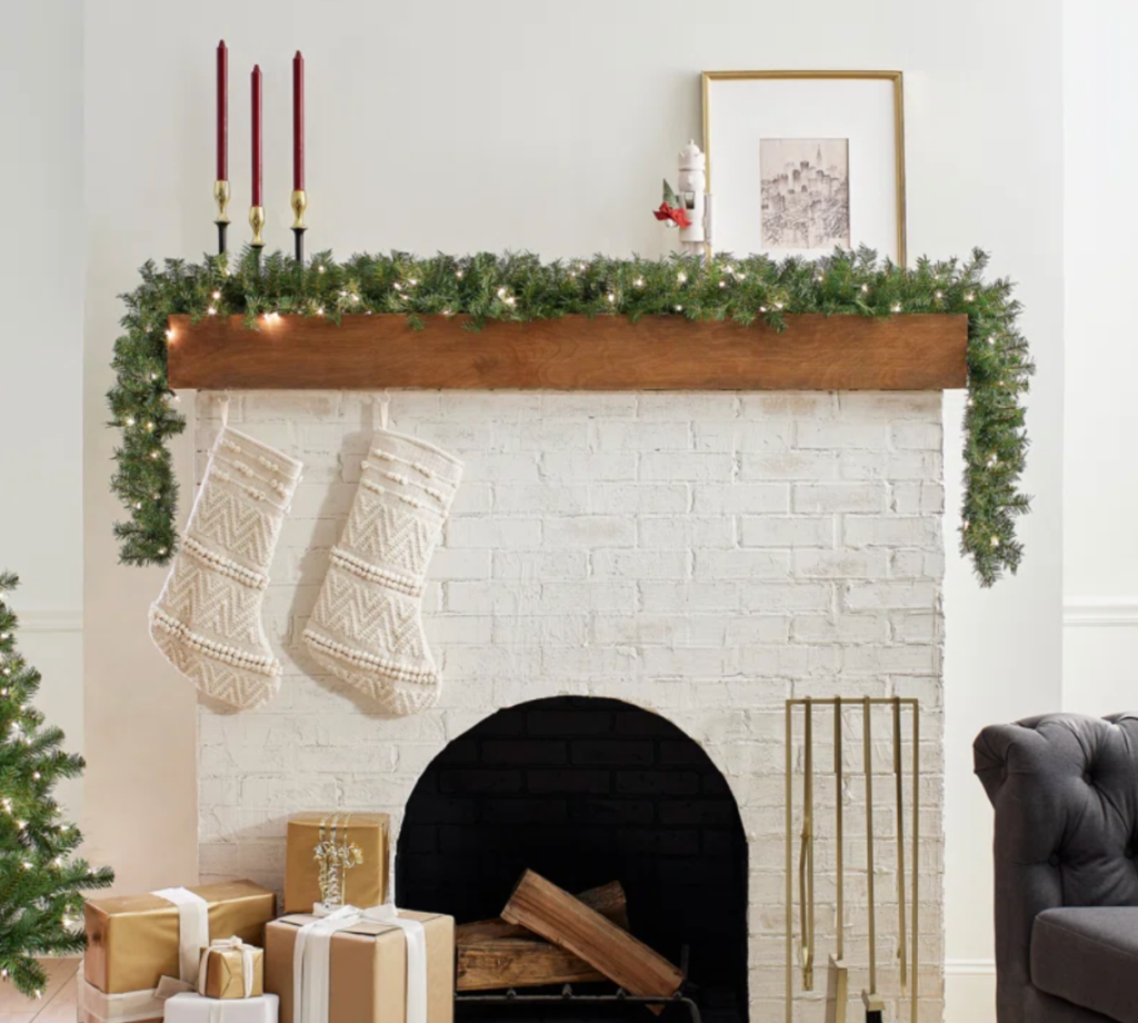 a string of pre-lit garland displayed on a fireplace mantle