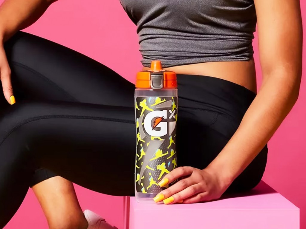 woman holding a grey and yellow gatorade bottle