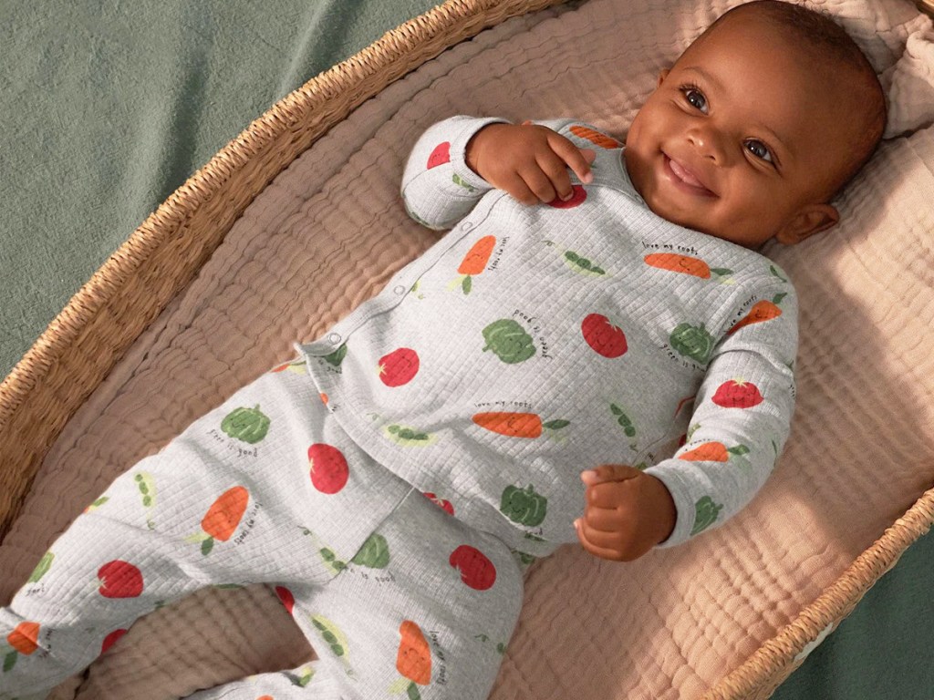 baby in a bassinet wearing matching grey outfit with vegetable print