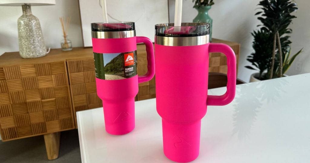 Hot Pink Ozark Trail Tumblers sitting on a counter, 1 had a label and the other doesn't