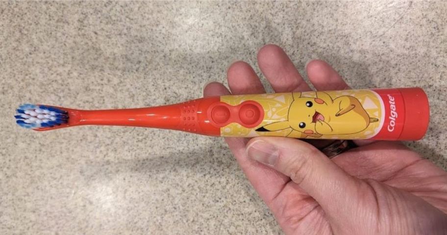 hand holding Colgate Kids Battery Toothbrush with Pokemon on it