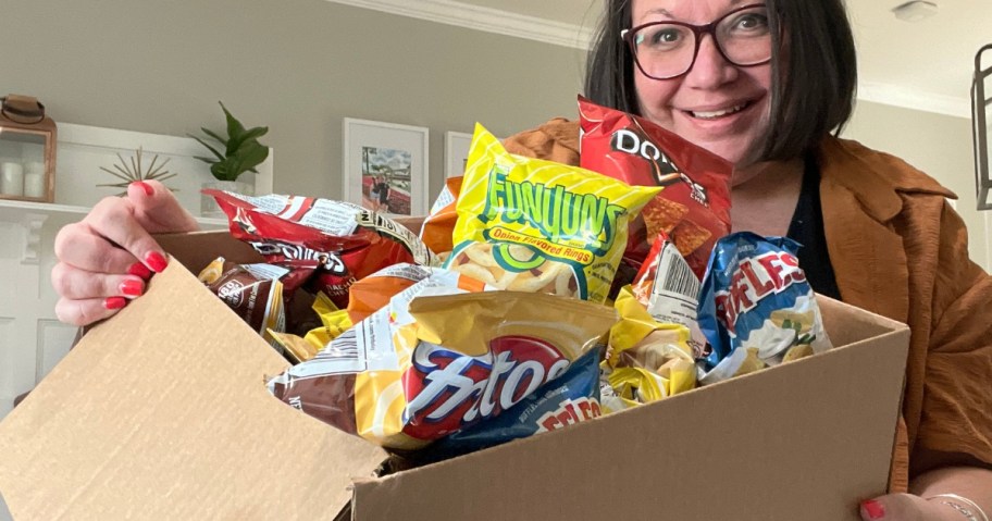 Lina holding a large box with a variety of Frito-Lay individual size chip bags