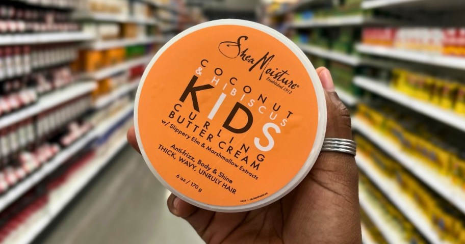 hand holding a container of SheaMoisture Kids Curling Styling Cream