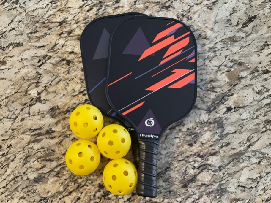 2 pickleball paddles and 4 pickleballs on a counter