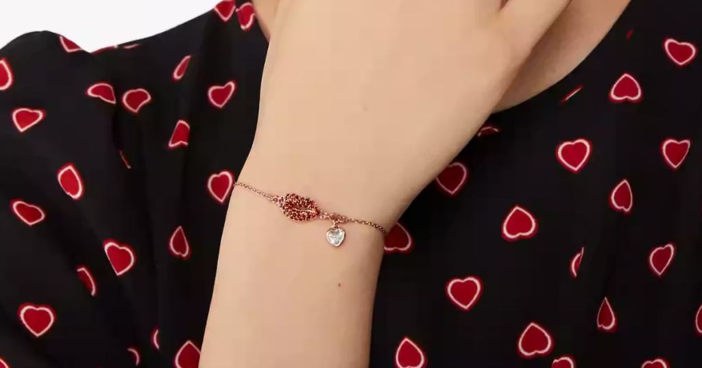 woman's wrist wearing a Kate Spade bracelet with red lip charm