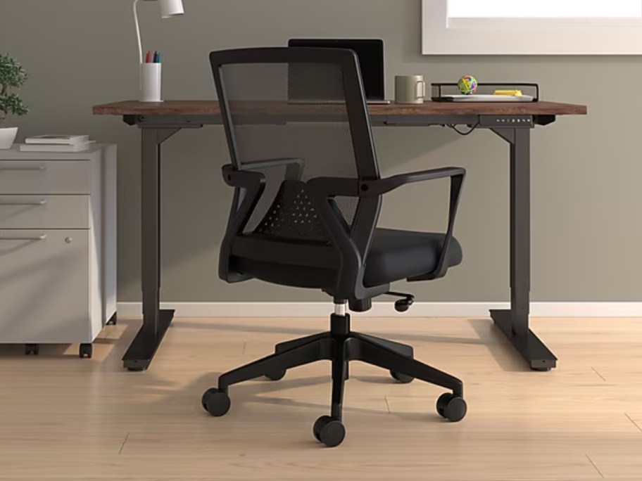 a black computer desk chair with wheels at a desk