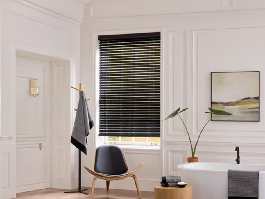 a home office with a chair and side table, window with a black wood blind