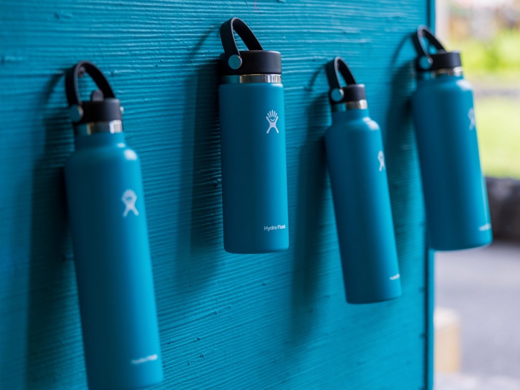 blue hydro flask bottles hanging from blue wall