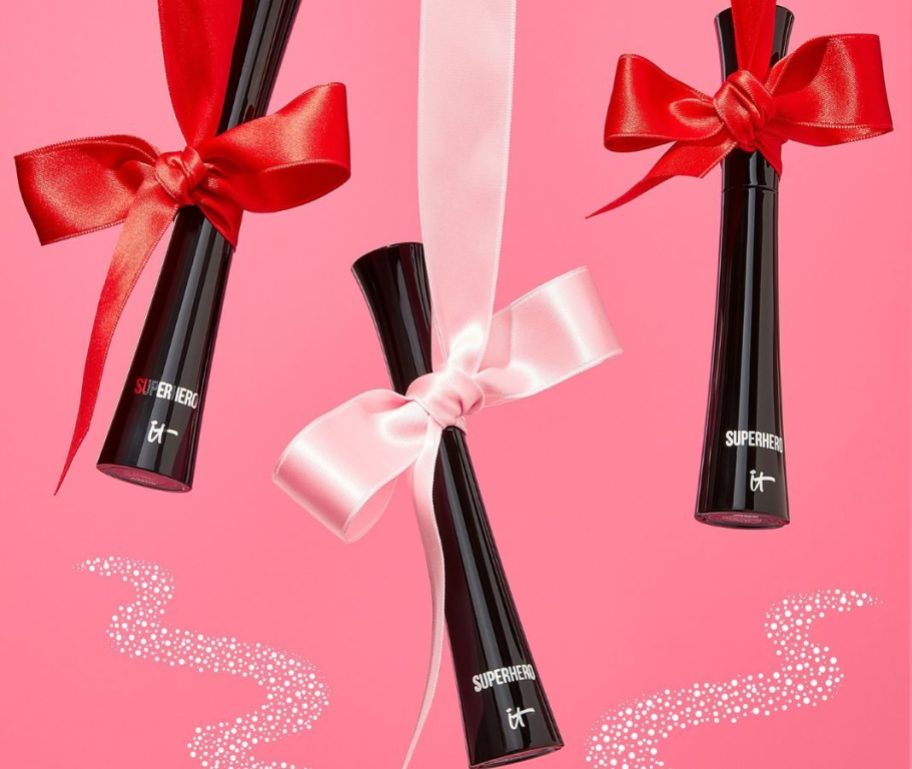 3 It Cosmetics Superhero Mascara hanging from red and pink ribbons