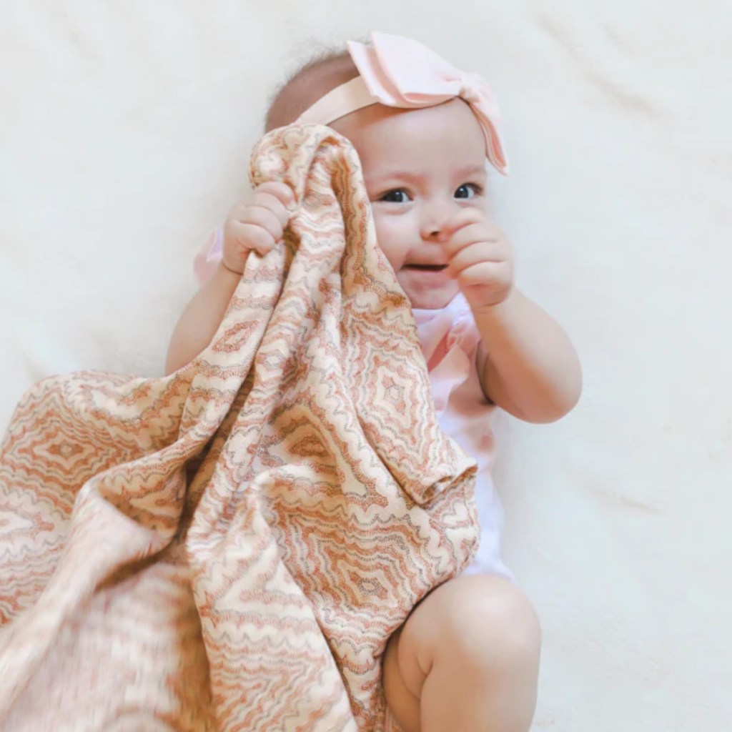 baby holding pink blanket 