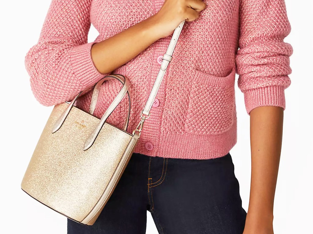 women in pink sweater with gold glitter bag