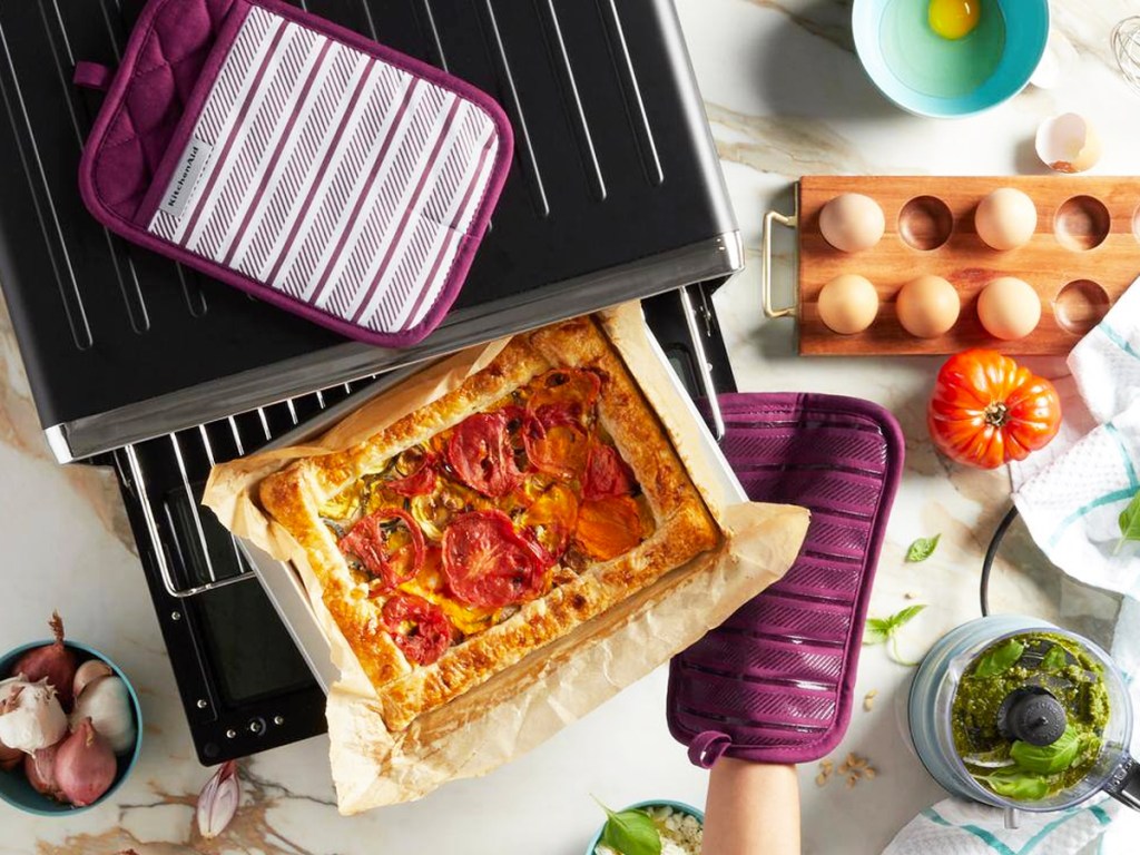 using purple pot holders to take pizza out from oven