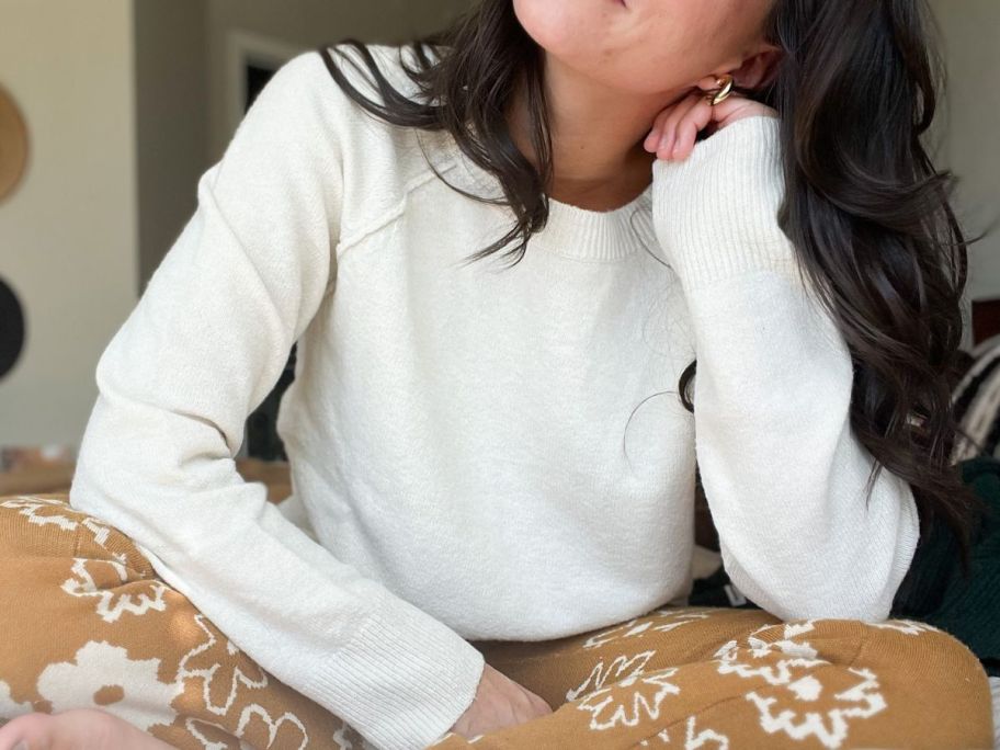 Girl sitting on a bed wearing a sweater from Kohl's
