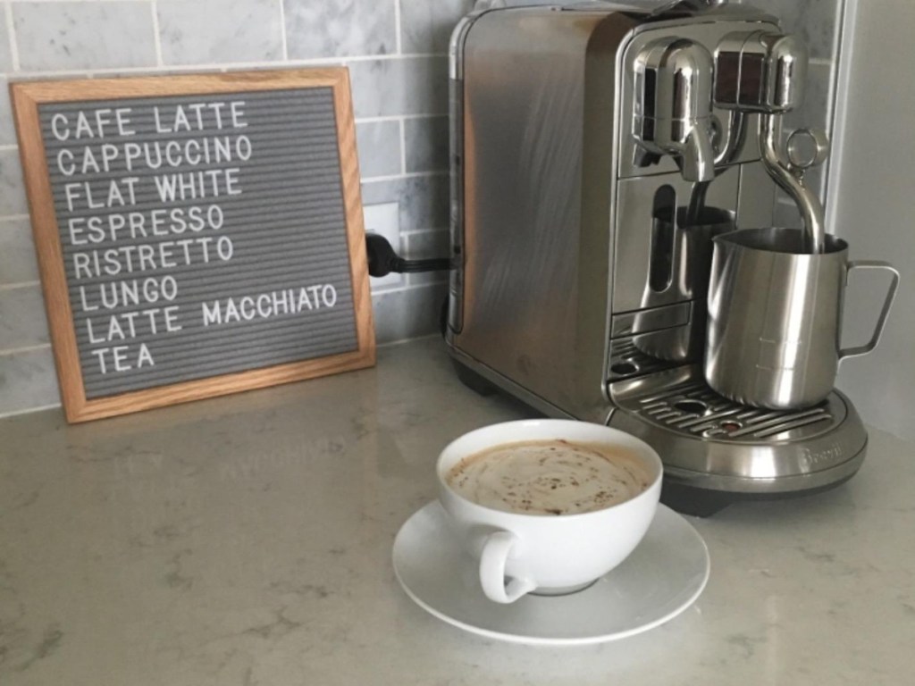 Latte machine with cup and felt board next to it in the kitchen