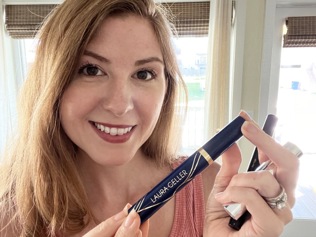 woman holding up a tube of laura geller mascara