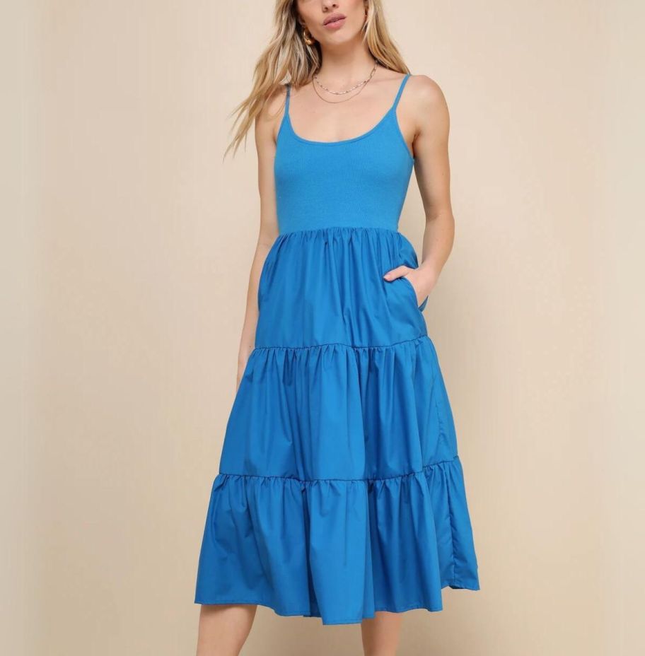 a model wearing a blue sleeveless tiered midi dress
