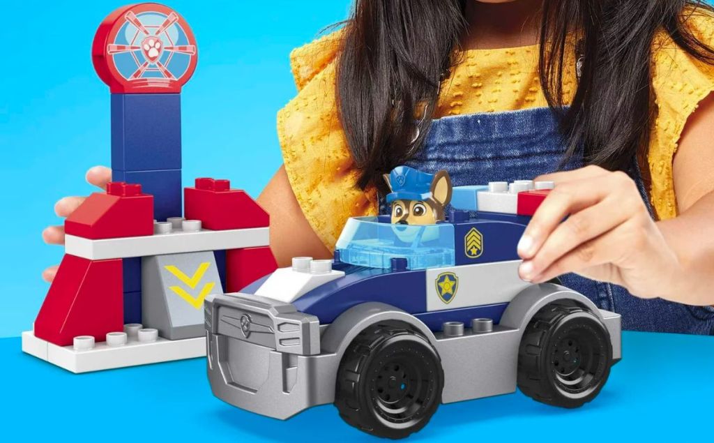a toddlers hands playing with a MEGA BLOKS PAW Patrol Toy Blocks Chase's City Police Cruiser