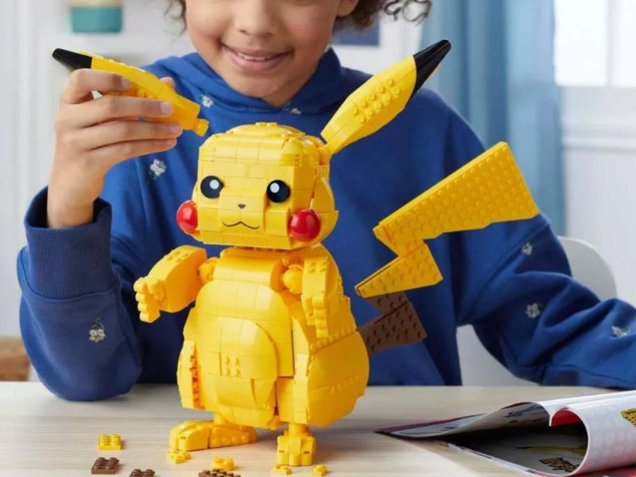 A child playing with a MEGA Building Jumbo Pikachu