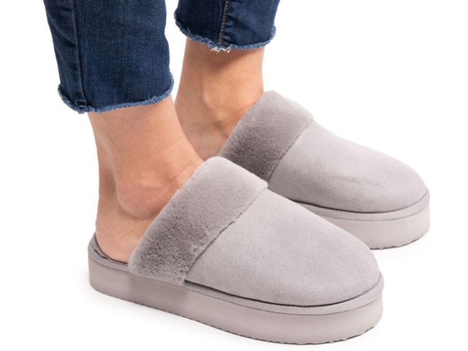a woman wearing a pair of MUK LUKS Women's Faux Fur Platform Scuff Slippers in gray