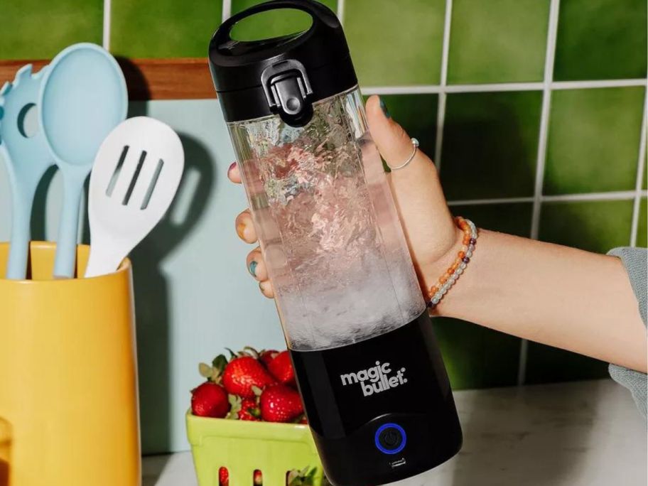 Hand holding a Magic Bullet portable blender filled with ice