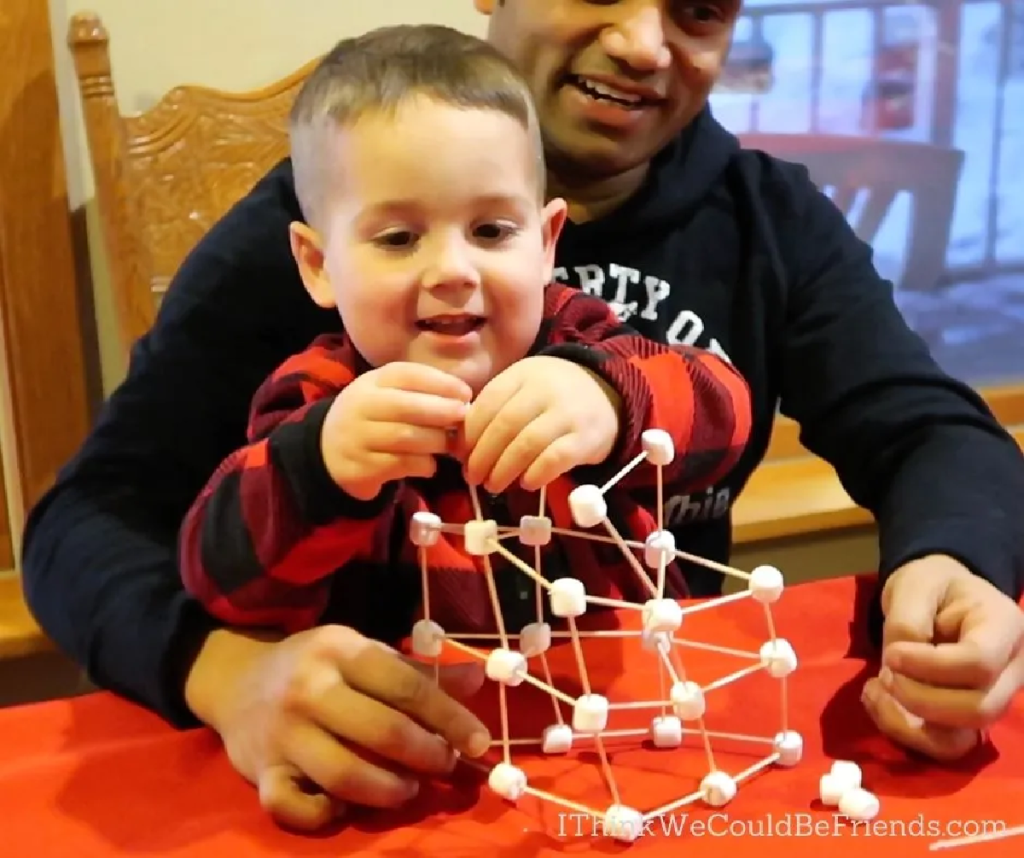 A dad and son playing the Marshmallow Towers Christmas party game