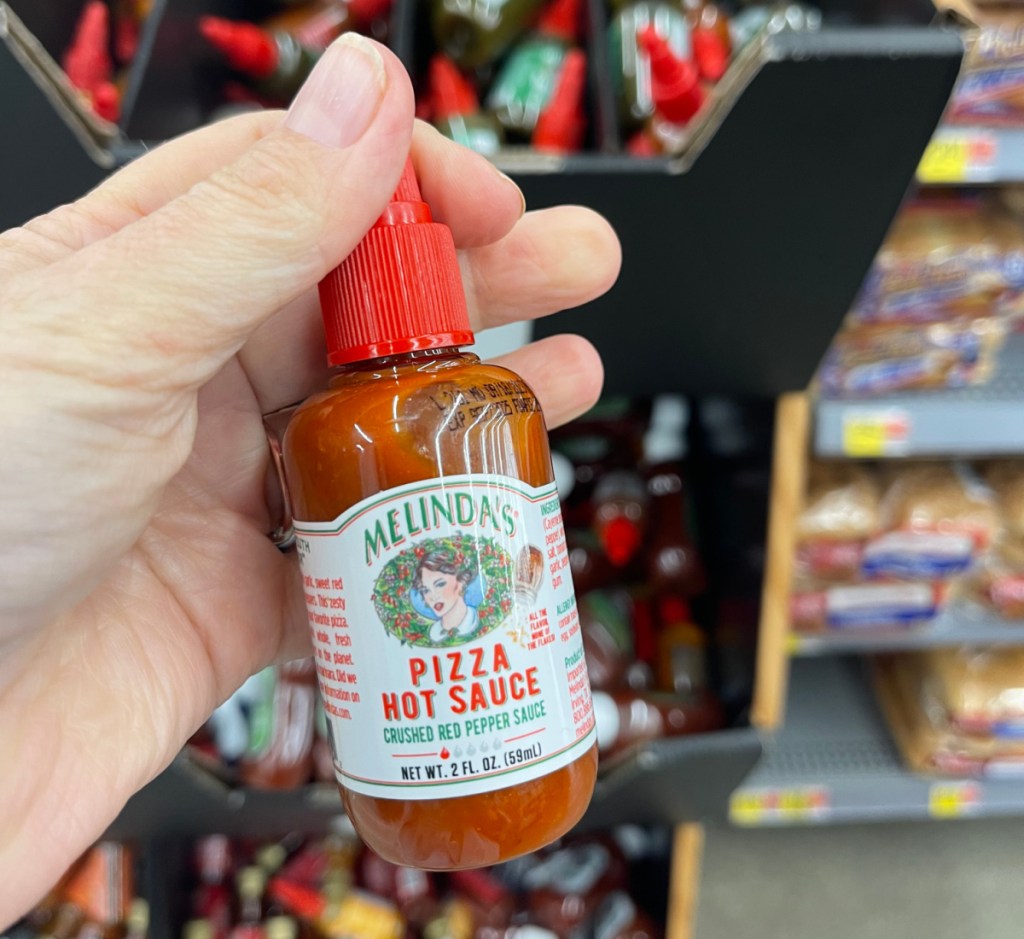 Hand Holding Melinda's Pizza Hot Sauce, a Walmart stocking stuffer idea that only costs $1