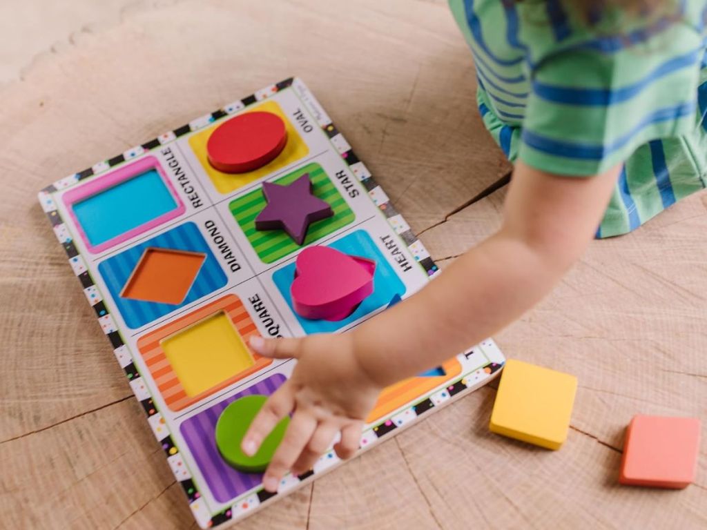 Little hand playing with a Melissa & Doug Chunky shapes puzzle