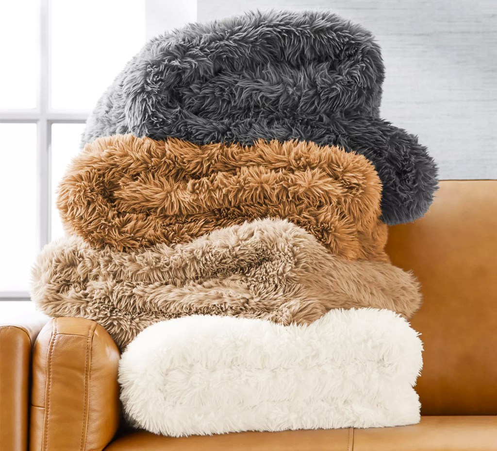 four fuzzy blankets folded on leather couch