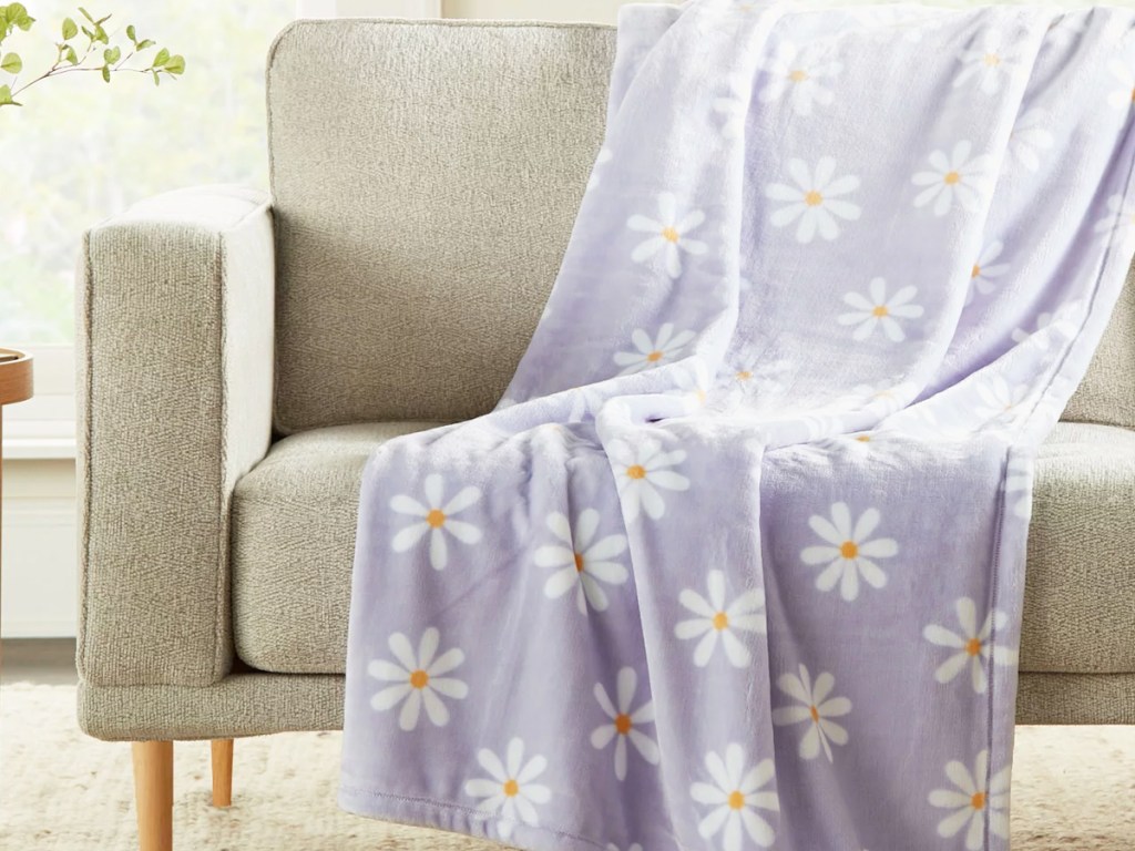 purple daisy print throw blanket draped on couch