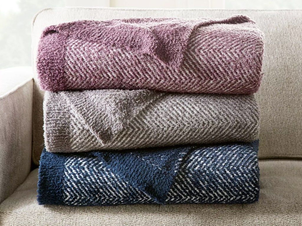 stack of folded throw blankets on couch