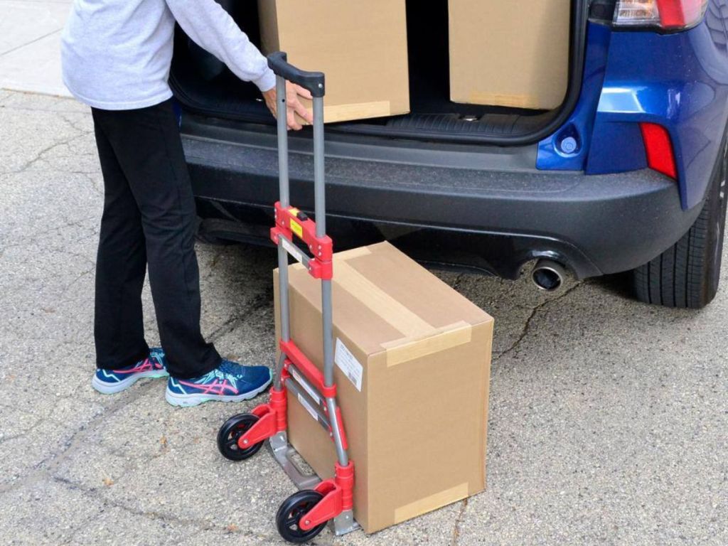 Woman using a Milwaukee Hand Truck to load boxes in a car
