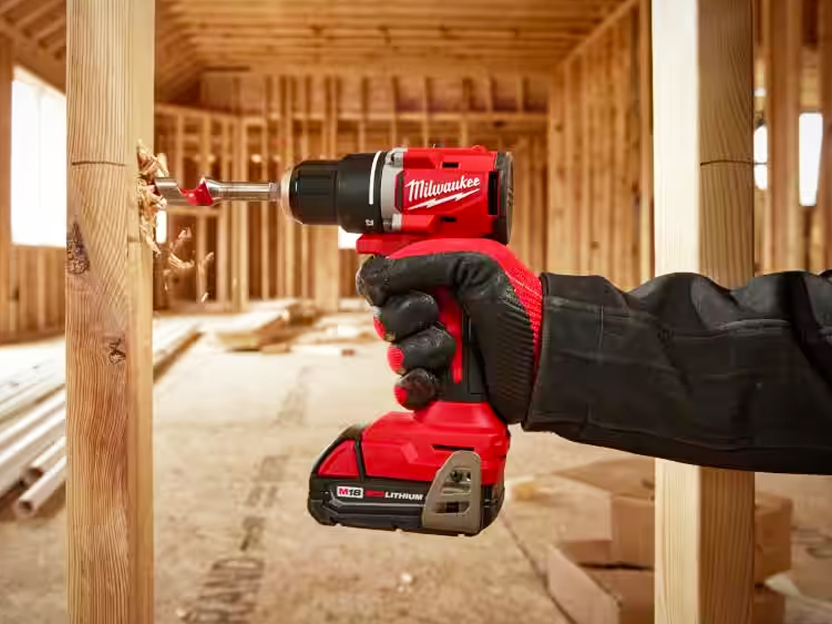 hand using red and black cordless drill